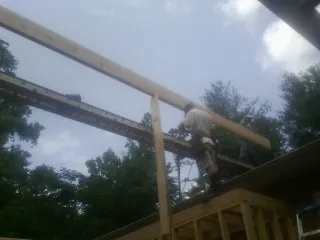 Carpenter setting a ridge beam over a new addition frame — Ice Dam Removal by Roofing Brothers in Elkridge