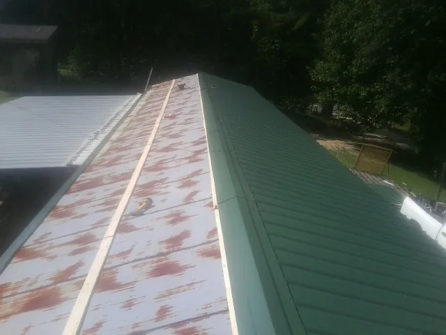 Old rusted panels beside newly installed green metal roofing — Wind Damage Roof Repair by Roofing Brothers in Elkridge