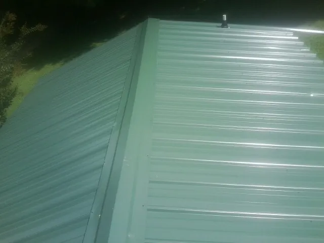New green metal panels meeting at the ridge of a roof — Flat Roof Repair work by our crew in Elkridge