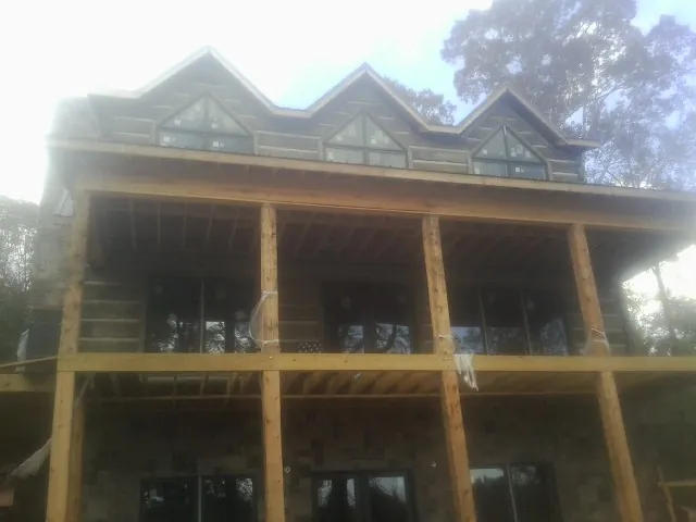 Dormers and porch framing on a large log home under construction — Roof Coating work by our crew in Elkridge
