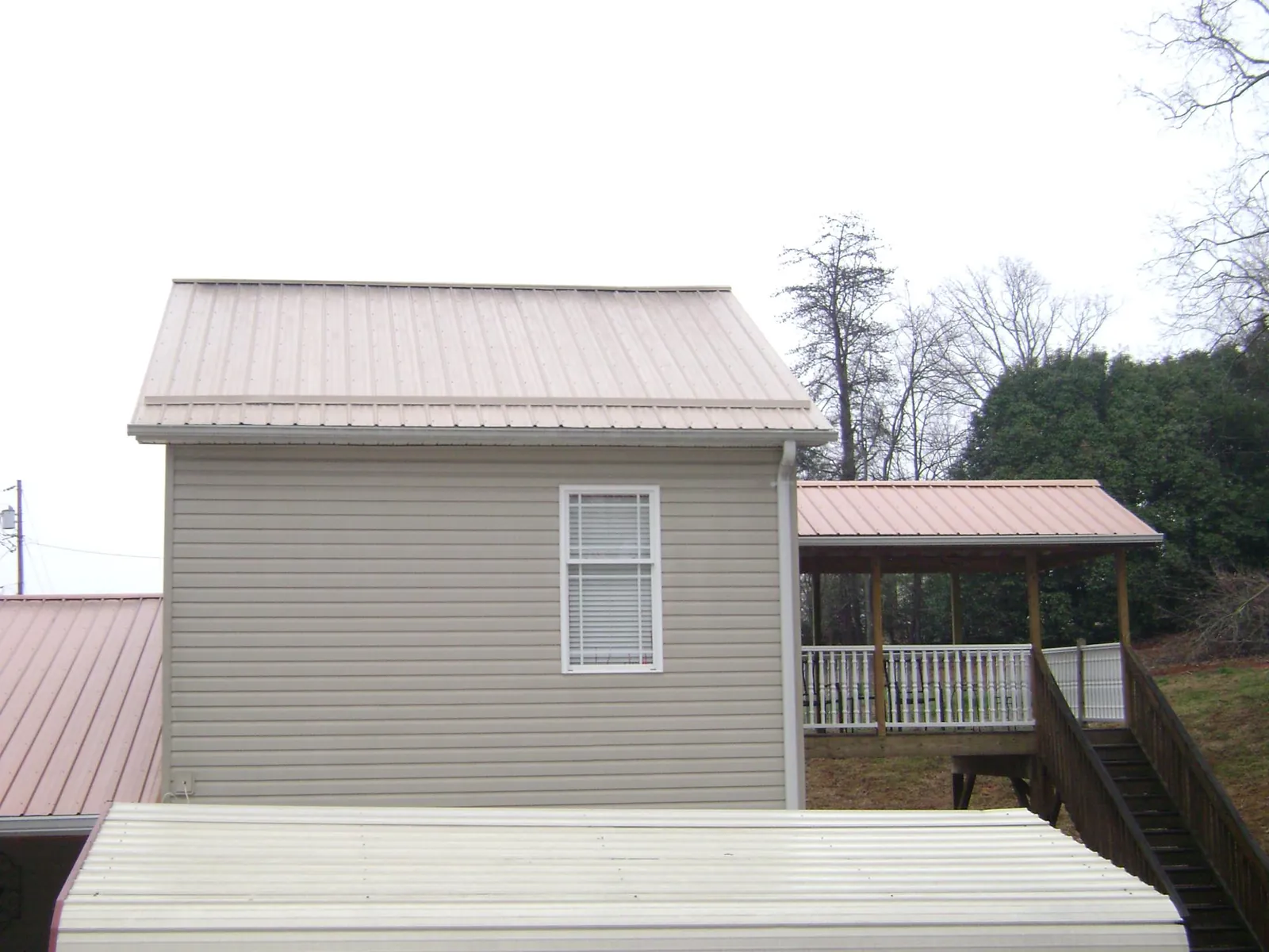 Tan metal roofs on a two story addition and attached porch, from a Roof Replacement job in Elkridge