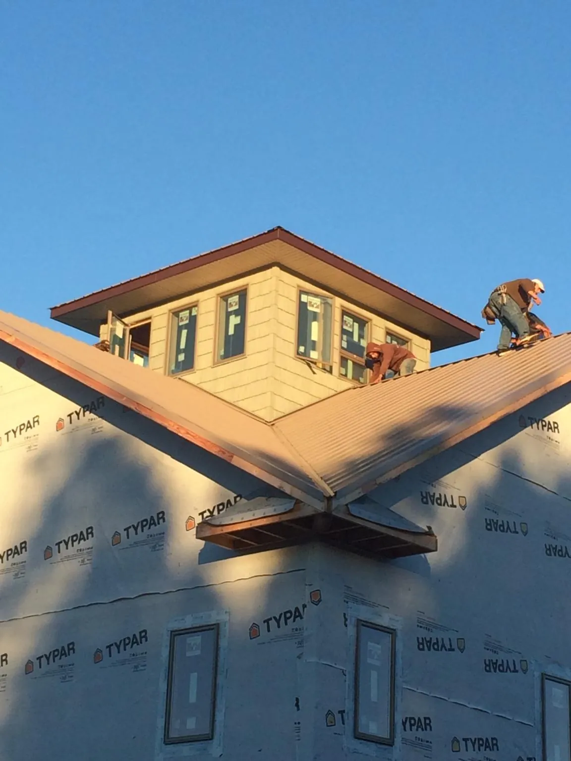Roofers working around a rooftop cupola on a new metal roof at sunset — Roof Waterproofing in Elkridge by Roofing Brothers